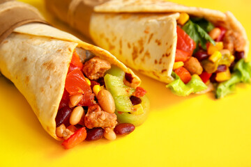 Delicious burritos on yellow background, closeup