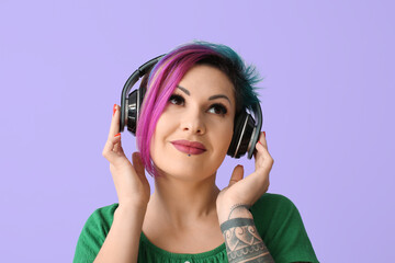 Fototapeta premium Beautiful woman with unusual hair and tattoo listening to music on color background