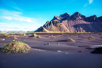 Scenic landscape with most breathtaking mountains Vestrahorn on the Stokksnes peninsula and cozy lagoon with green grass on the sand dunes in Iceland. Exotic countries. Amazing places.