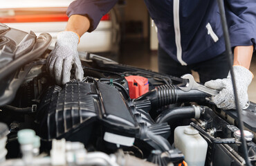 Fototapeta premium Automobile mechanic repairman hands repairing a car engine automotive workshop with a wrench, car service and maintenance,Repair service.