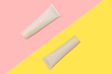 Two white plastic containers. On a pink and yellow background.