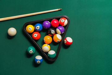Different billiard balls with cue and rack on green table - obrazy, fototapety, plakaty