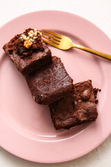 Plate with pieces of tasty chocolate brownie on white background
