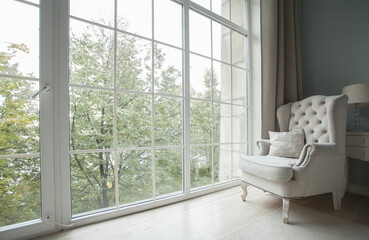 Fototapeta na wymiar Light color livingroom interior background. Armchair near window with gardens view