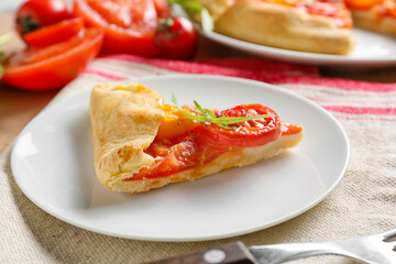 Plate with piece of tasty tomato galette on table, closeup