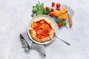 Plate with tasty tomato galette on light background