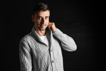 Handsome young man in knitted sweater on dark background