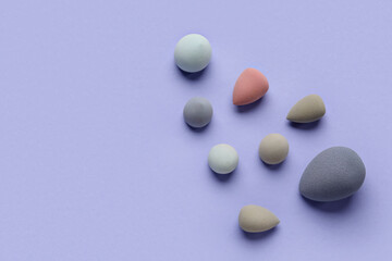 Different makeup sponges on purple background