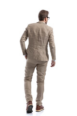 Naklejka premium businessman walking with a hand in pocket, looking to side