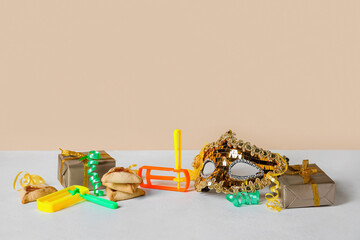 Tasty hamantaschen and decor for Purim holiday on table against beige background