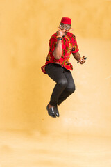 Igbo Traditionally Dressed Business Man in Mid Air with Phone in Hand and fist Pump