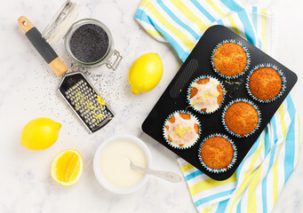 Freshly baked muffins with poppy seeds, lemon zest and icing sugar on a marble background. The concept of home baking. Citrus dessert. Breakfast for gourmets.  Selective focus, top view