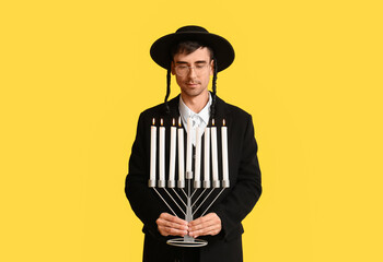 Jewish man with menorah on color background