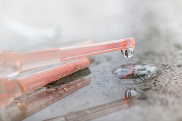 Close-up of water dripping from a plastic pipette on a bright background