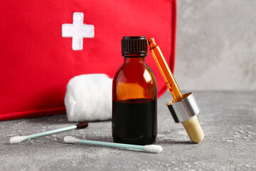 Bottle with iodine, pipette, cotton swabs and first aid kit on grunge background