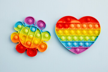 Top view of colorful anti stress sensory toys pop it rainbow heart and flower on blue background close up. Creative and funny concepts of children toys. Popular toy. Trend toy 2021-2022 year.