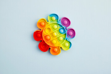Top view of colorful anti stress sensory toy pop it rainbow flower on blue background close up. Creative and funny concepts of children toys. Popular toy. Trend toy 2021-2022 year.