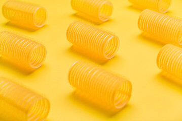 Fototapeta premium Set of hair curlers on yellow background, closeup