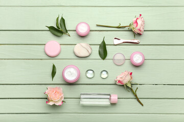 Composition with jars of natural cosmetic cream and flowers on color wooden background