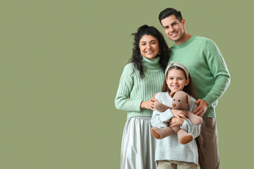 Happy parents with little daughter in warm sweaters on green background