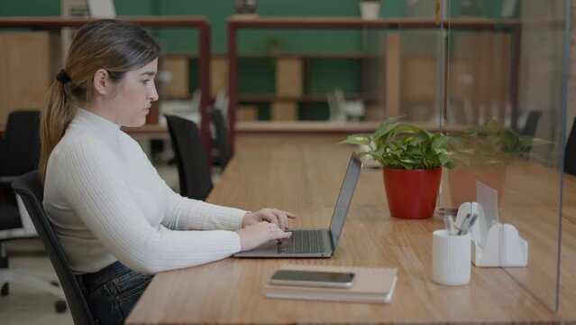 Portrait of pensive woman entrepreneur using a laptop while working in an open office, copy space - sliding shot