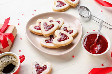 Plate with tasty cookies and cup of coffee for Valentine's Day celebration on light background