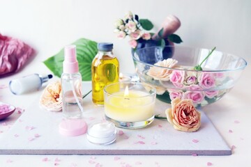 Spa, fresh pink roses, burning candles, oils and tinctures on a light background, healthy lifestyle, relaxation, home cosmetics, aromatherapy, romantic mood, alternative medicine