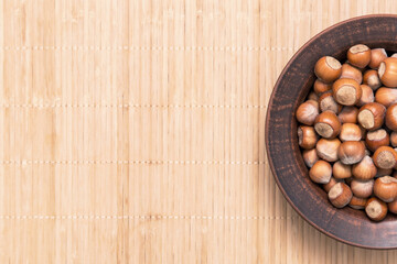 Hazelnut nuts in clay plate top view, flat lay. Nut on rustic brown background, copy space