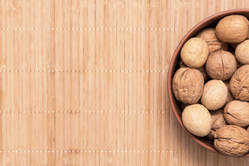 Walnut nuts in plate top view, flat lay. Nut on rustic brown background, copy space