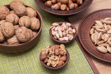 Nuts mix. Walnut, hazelnut, almond, pistachio in brown clay plate on table