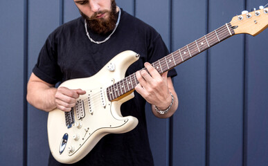Obraz premium Young street musician playing guitar near the big blue wall