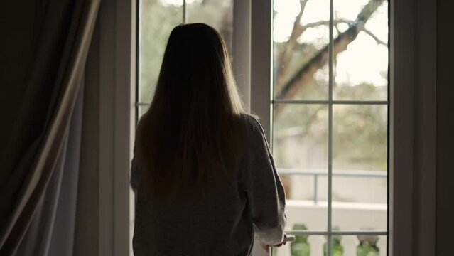 Woman opening curtains in hotel room going out on the balcony, slow motion