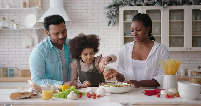 Parents help mixed race daughter cook according to recipe