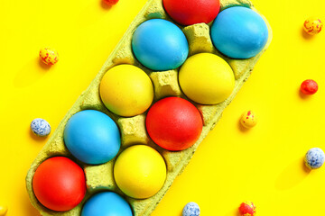 Holder with multicolored Easter eggs on color background