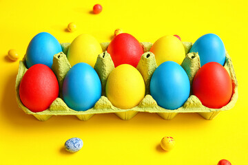 Holder with multicolored Easter eggs on color background