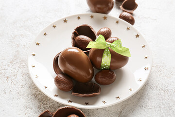 Plate with chocolate Easter eggs on light background