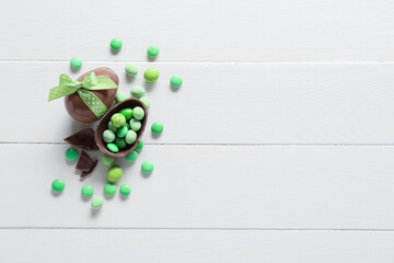 Chocolate Easter eggs with candies on white wooden background