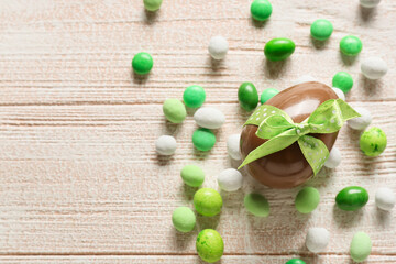 Chocolate Easter egg with candies on white wooden background