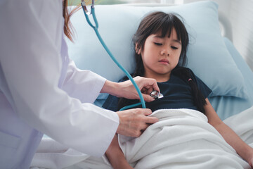 Asian woman pediatrician doctor hold stethoscope for exam a little girl patient and heck heart lungs of kid, Good family doctor visiting child at home, Healthcare and medicine for childhood concept.