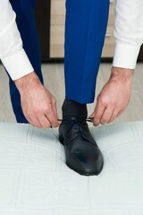 A young man ties the laces of his shoes - detail, selective fokus
