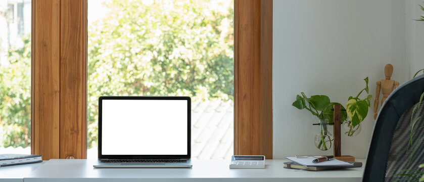 Blank screen laptop computer in minimal office room with calculatpr and decorations and copy space.