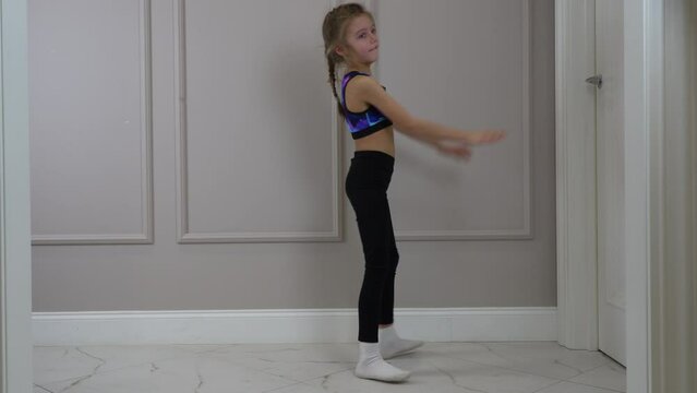 little girl in sports clothes doing bridge pose on the floor in a living room