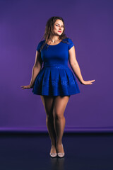 Happy plus size model in blue dress on purple background