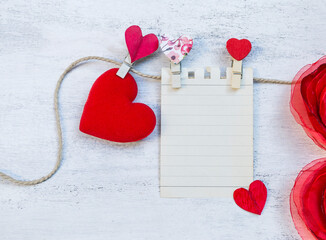 Valentine concept background, blank paper note with red heart and fabric flower on white texture background