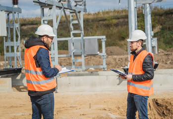 Obraz na płótnie Canvas Two engineer electricians check the substation construction process