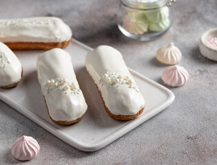 white chocolate glaze eclairs on serving board. Traditional French dessert. selective focus