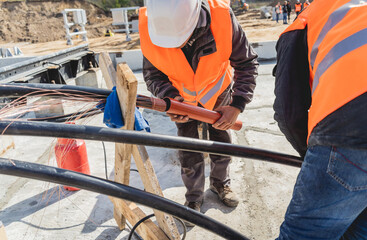 Two electrician builder workers installing high-voltage cable