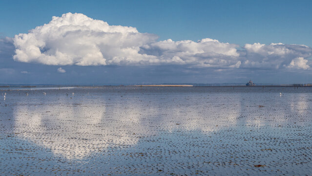 nuage de type cumulonimbus refl&eacute;tant dans l'eau de la baie du mont Saint Michel en Bretagne