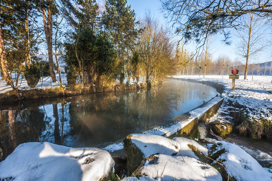 rivi&egrave;re et berges enneig&eacute;e avec arbres d'un c&ocirc;t&eacute; et pr&eacute; de l'autre