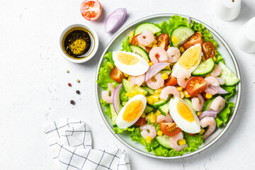 Summer colourful shrimp egg vegetable salad on plate on light background. Top view, copy space.